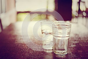 Drinking cold water into a three glass placed on the wooden table.