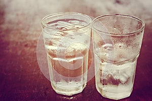 Drinking cold water into a three glass placed on the wooden table.