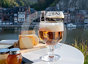 Drinking of dark and strong Belgian abbey beer with cheeses with nice view on Maas river and town Dinant, Belgium
