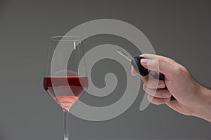 Drinking and driving concept shot. Male hand holding car keys next to tall wine glass, studio shot