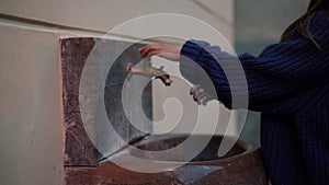 Drinking fountain. Girl walks to the fountain, opens golden tap and washes her hands, in close-up