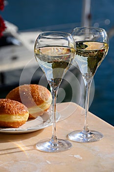 Drinking of French brut champagne sparkling wine with sweet apple Beignet, club party in yacht harbour of Port Grimaud near Saint-