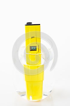 drinking glass with ph meter water tester in action white background