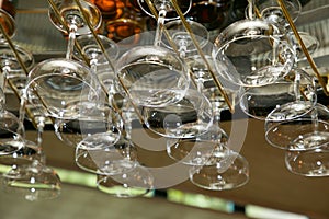 Drinking glasses hanging from a rack in a bar or restaurant.