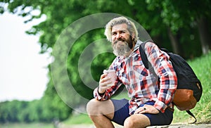 Drinking hot coffee. Drink tea or coffee. Man with cup outdoors. Enjoying nature at riverside. Guy with backpack