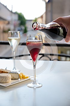 Drinking of Kir Royal,  French aperitif cocktail made  from creme de cassis topped with champagne, typically served in flute glass