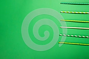Drinking paper colorful straws for summer cocktails on light green background with copy space. Top view.