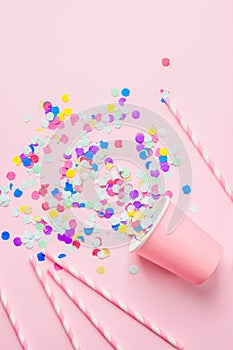 Drinking Paper Cup Striped Straws Colorful Confetti Scattered on Fuchsia Background. Flat Lay Composition. Birthday Party Kids