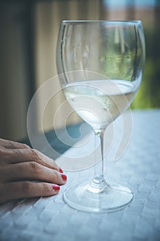 Drinking problem: Glass of white wine, hand of a woman with red nail polish