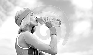 Drinking during sport. Young woman drinking water after run. Woman in sports wear is holding a bottle of water. Sports