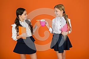 Drinking tea while break. School mates relaxing with drink. Enjoy being pupil. Girls kids school uniform orange