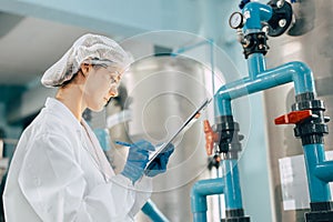 Drinking water factory purification process. Hygiene factory worker female monitor checking valve and water pipe production flow