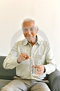 Drinking water is good healthy habit for old man, Elderly smiling asian man pointing at glass of purified water.