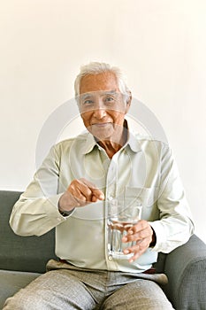 Drinking water is good healthy habit for old man, Elderly smiling asian man pointing at glass of purified water. photo