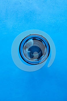 Drinking water with ice in transparent blue glass on blue background. Top view, selective focus, copy space