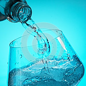 Drinking water is poured into a glass from a bottle