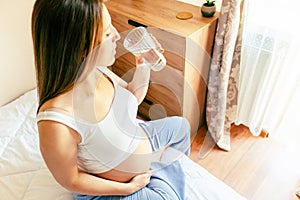 Drinking water pregnant woman. Young pregnancy mother drink water. Pregnant lady waiting of baby. Glass of water