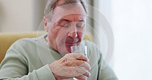 Drinking water, senior man and Parkinson disease or tremor with trembling hands on a home sofa. Sick elderly person with