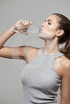 Drinking water, wellness and woman with bottle in studio for healthy body, refreshing and hydration. Diet, fitness and
