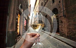 Drinking wine on street. Hand of a happy drinker in outdoor cafe of narrow historical area, enjoying alone