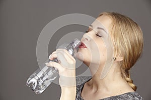 She drinks mineral water out of a plastic bottle