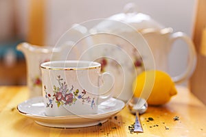 Drinks, relaxation and tea party concept - tea-set of cup, pot, spoon, lemon and saucer