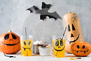 Drinks sweets and pumpkins with frightful faces on table