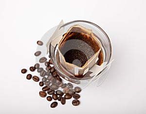 Drip bag of fresh coffee in a glass with coffee beans isolated on white background.