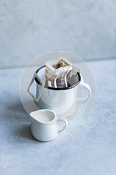 Drip or brewed coffee on gray background, paper dripping bag on a white cup. Specealty coffee at home