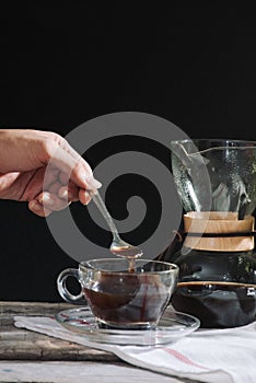 Drip brewing coffee concept. Wooden desk with chocolate cake and cup of coffee on black background