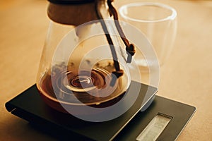 Drip coffee. Coffee drops closeup from filter in glass kettle on scale. Brewing aromatic fresh alternative coffee, v60 closeup.