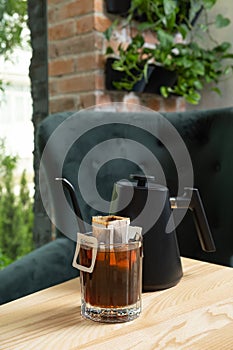 Drip coffee in a glass cup on a wooden table in the interior of a cafe