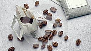 Drip coffee paper bags with coffee beans on a grey concrete