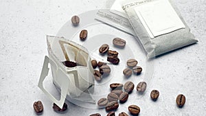 Drip coffee paper bags with coffee beans on a grey concrete