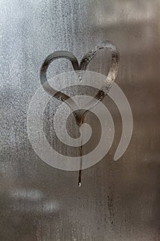 Drip in the shape of a heart on a misted window-glass. Close-up. Background