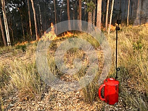 A drip torch with fire in the background