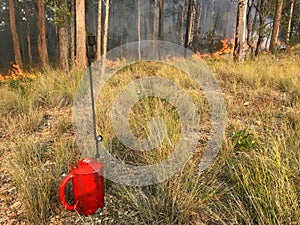 A drip torch with fire in the background