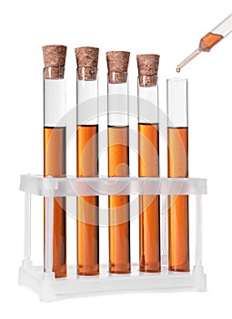 Dripping brown liquid from pipette into test tube on white background