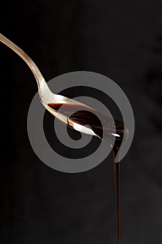Dripping caramel from a spoon on a dark background. Liquid sweetness