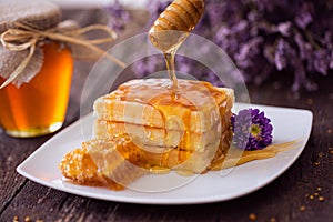 Dripping honey from a wooden dipper on fresh waffle