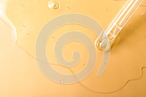 Dripping hydrophilic oil from pipette on beige background, top view