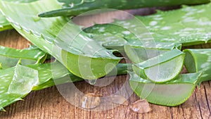 Dripping juice from sliced pure aloe vera leaf on wooden board. Sliced aloe vera leaves with transparent gel drops closeup