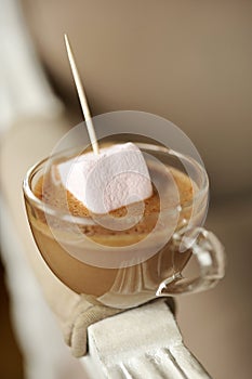 Dripping a marshmallow in a cup of chocolate cream