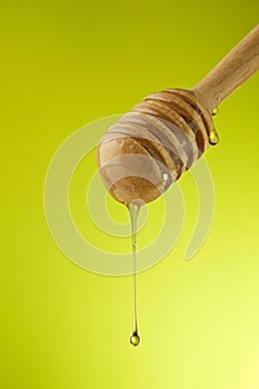 Dripping organic honey with honeycomb on yellow background