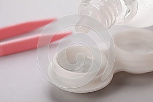 Dripping solution into case with contact lenses on white background, closeup