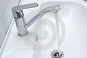 Dripping water from the single handle mixer tap mounted on a wash basin