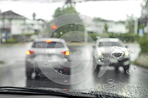 Drive a car on the road stop with traffic light with raindrop over the wind shield. Shot form wind shield