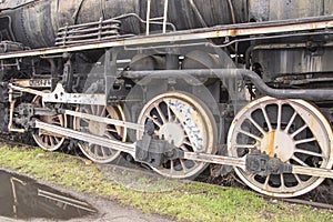 Drive transmission mechanism in a historic and damaged steam locomotive standing on a sidetrack. Rail