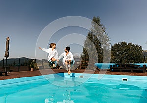 Drive young couple together by hand jumping into the pool