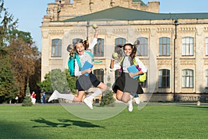 Driven and energetic. Energetic children in midair outdoors. School girls in energetic jump. Back to school fashion